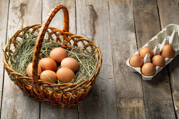 istock Chicken eggs in a hay basket and egg tray, on a wooden table. 1319422486
