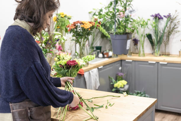 エプロン、若い女性起業家の概念を身に着けている彼女の花屋で緑と紫の花束を設計する女性のビュー。 - orchid flower single flower green ストックフォトと画像