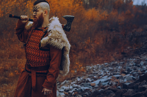 Brutal scandinavian warrior with axe posing outdoors