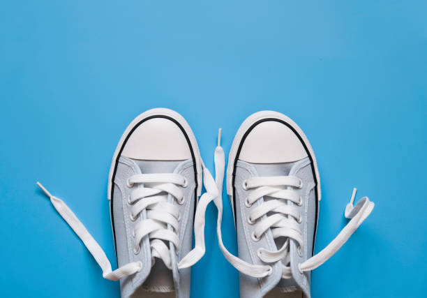 istock blue sneakers with white laces on a blue background. 1319426567
