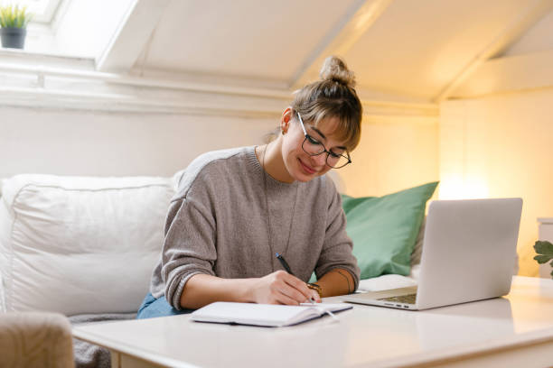 istock Young woman taking notes at home 1319429585