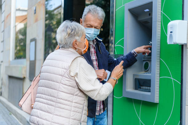 un couple de personnes âgées utilisent un guichet automatique pendant un temps de virus. - model70 photos et images de collection