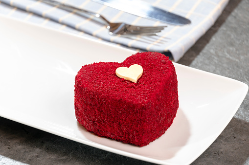 A heart shaped red cake inside the plate.