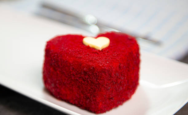 A cake in heart shape. One heart-shaped mousse cupcake on a plate on a purple background. Valentine's Day.