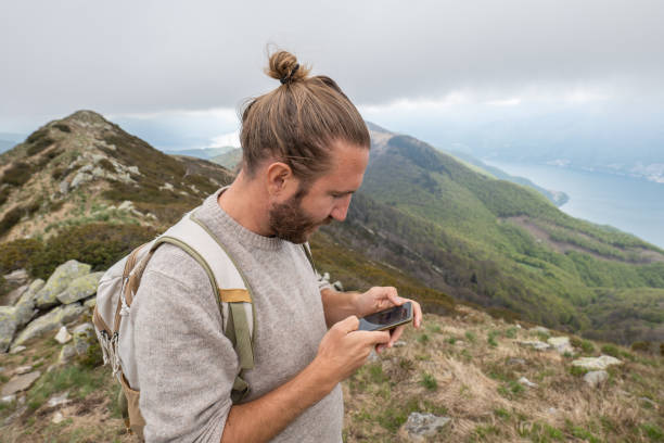 istock Man hiker uses phone on mountain trail 1319438402