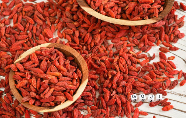 Word GOJI on small white cubes (necklace beads) ,dried wolfberry seeds in wooden bowls and spilled over boards desk near Word GOJI on small white cubes (necklace beads) ,dried wolfberry seeds in wooden bowls and spilled over boards desk near wolfberry berry berry fruit red stock pictures, royalty-free photos & images