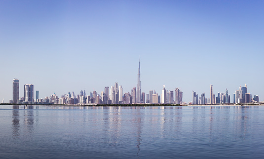 Dubai Downtown skyline panorama with reflections in Dubai Creek, cold colors, United Arab Emirates. High resolution.