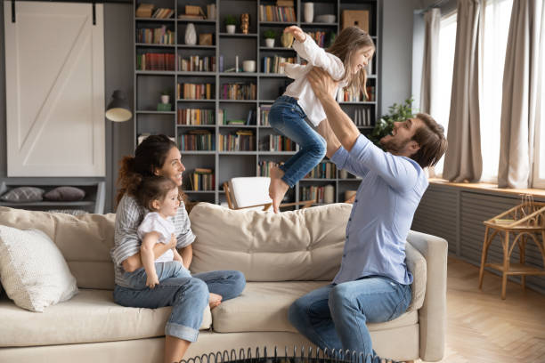 istock Smiling parents play with little daughters at home 1319451794