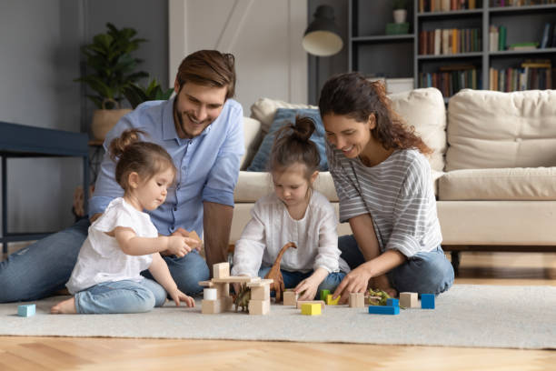istock Loving parents play with little daughters at home 1319451807