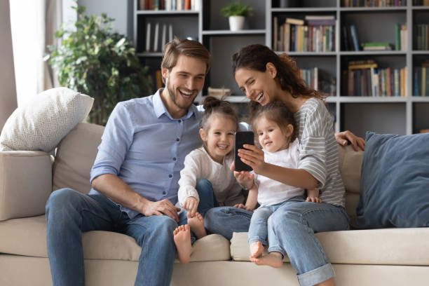 istock Happy parents use cellphone with two small daughters 1319451814