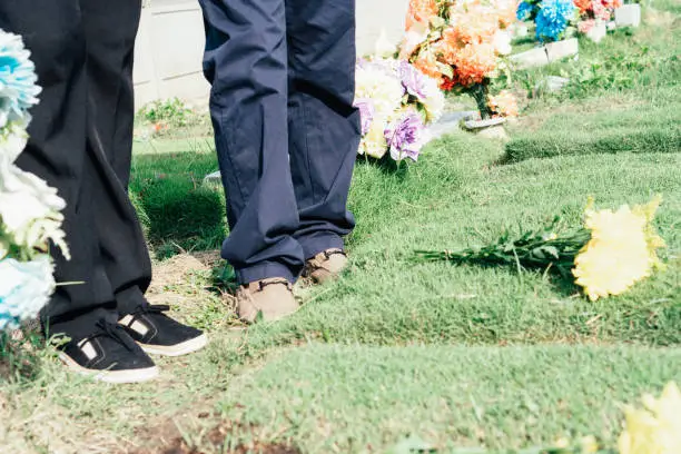 Unrecognizable couple at cemetery visiting a relative commemorating their ancestors