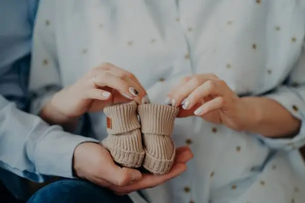 Newborn baby boots. Cropped shot of future woman and man ready to become parents holds childrens shoes. Waiting for infant. Happy family concept