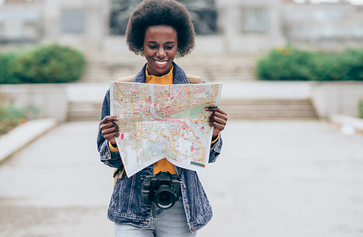 Beautiful smiling African-American woman holding a city map, checking out where to go next.