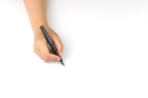 Cropped of a woman hand holding a fountain pen is writing on white paper, focus on the hand and with the space for your own text messages.