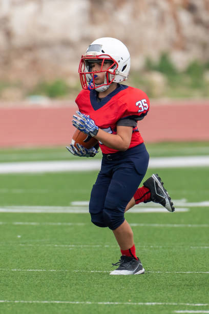 Athletic Young Boy Playing in a Football Game Athletic Football player catching and running with the ball during a game broad catch stock pictures, royalty-free photos & images