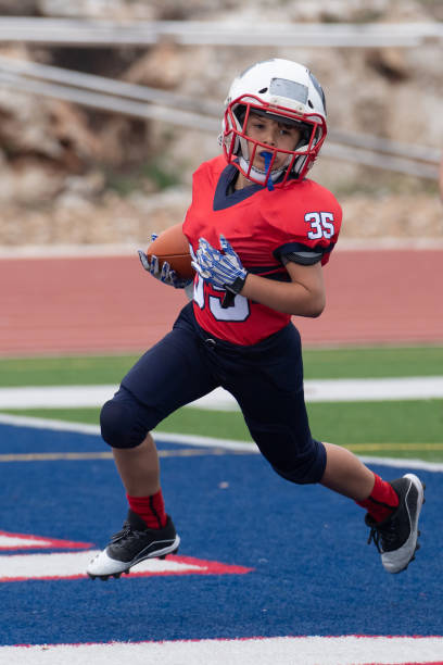 Athletic Young Boy Playing in a Football Game Athletic Football player catching and running with the ball during a game broad catch stock pictures, royalty-free photos & images