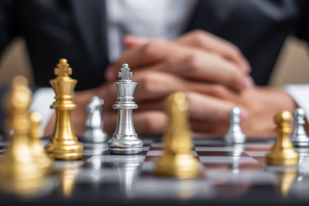 istock chess King figure against chessboard opponent with businessman manager background. Strategy, Success, management, business planning, tactic, politic, thinking, vision and leadership concept 1319462818