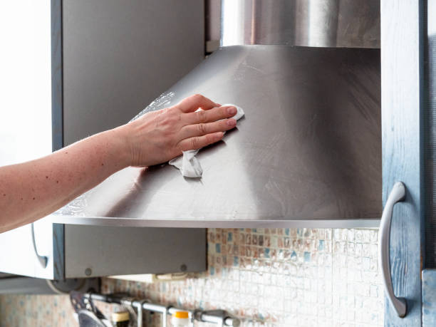 hand washes polished steel kitchen hood at home stock photo