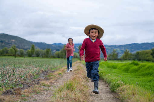 Happy Latin American kids playing outdoors at a farm and running on the road - lifestyle concepts
