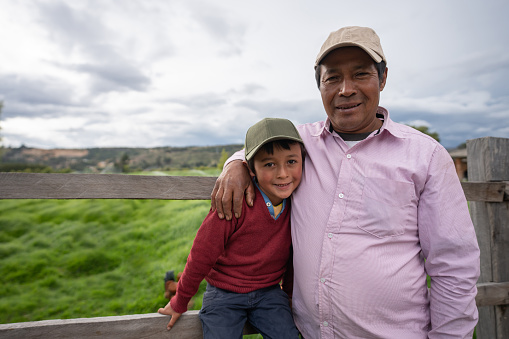 Portrait of a loving Latin American father and son looking happy at a farm and smiling outdoors - agricultural lifestyle concepts