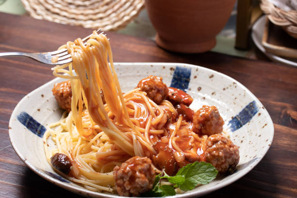 istock The hand was holding a fork, cutting spaghetti, ketchup, meatballs. 1319469277