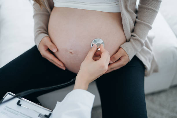 cropped shot of pregnant woman having a consultation with doctor during routine check up at clinic. doctor is performing an examination on the belly with stethoscope. check-ups, tests and scans to ensure a healthy pregnancy for both mother and unborn baby - human pregnancy midwife healthcare and medicine visit imagens e fotografias de stock