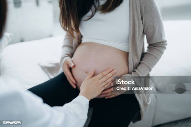 Cropped Shot Of Asian Pregnant Woman Having A Consultation With Doctor During Routine Check Up At Clinic Doctor Is Performing An Examination And Touching The Belly Checkups Tests And Scans To Ensure A Healthy Pregnancy For Both Mother And Unborn Baby Stock Photo - Download Image Now