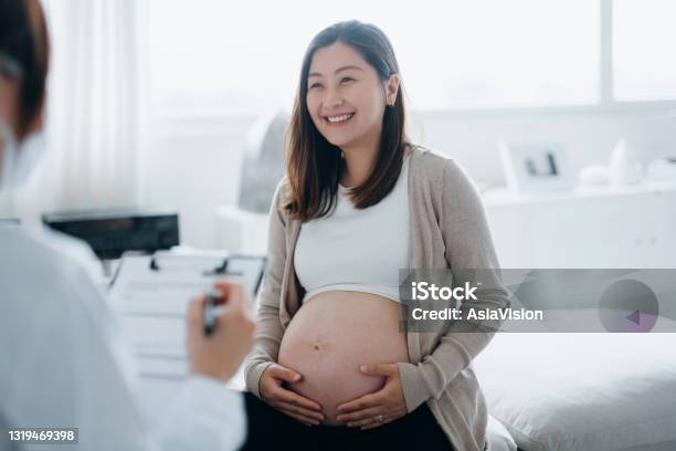 Smiling Young Asian Pregnant Woman Having A Consultation With A Female Doctor During Her Routine Check Up At A Clinic Checkups Tests And Scans To Ensure A Healthy Pregnancy For Both Mother And The Unborn Baby Healthy Pregnancy Lifestyle Stock Photo - Download Image Now