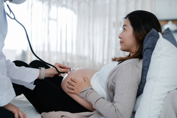 cropped shot of pregnant woman having a consultation with doctor during routine check up at clinic. doctor is performing an examination on the belly with stethoscope. check-ups, tests and scans to ensure a healthy pregnancy for both mother and unborn baby - human pregnancy midwife healthcare and medicine visit imagens e fotografias de stock