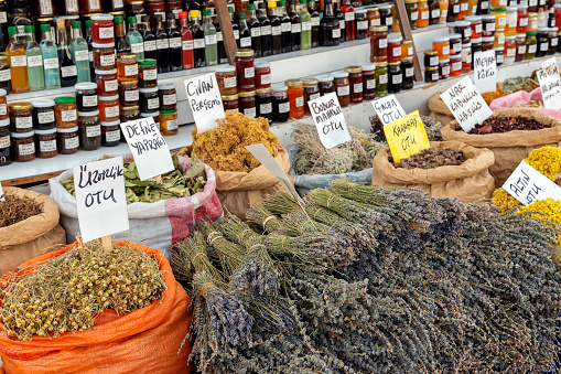 Different kinds of dried herbs at street market in Izmir, Turkey. Homemade jam jars on the background.
