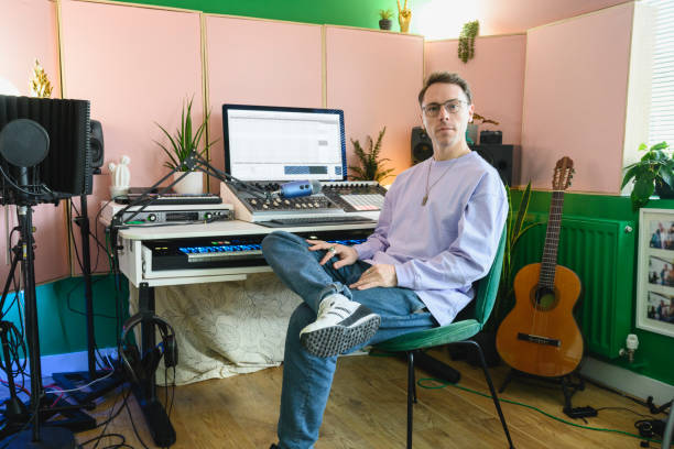 istock Musician in mid 30s sitting at mixing console in home studio 1319473934