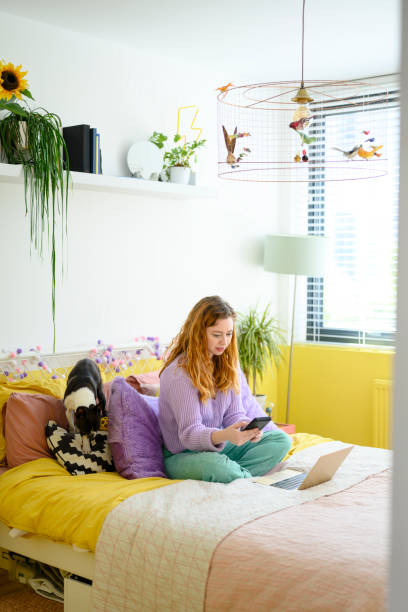 istock Casually dressed woman using phone and laptop at home 1319473948