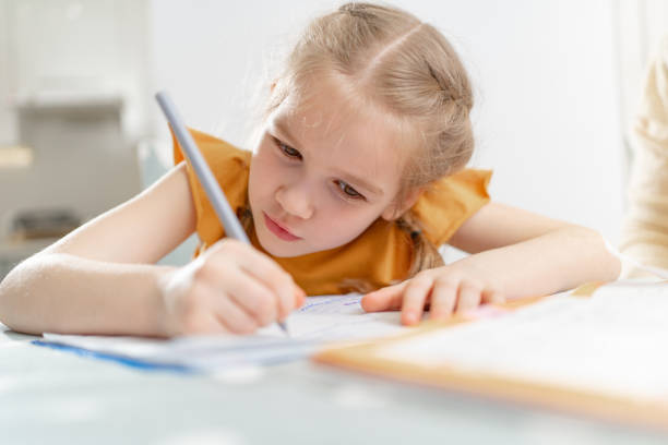 istock A concentrated and diligent little schoolgirl does her homework. 1319479653