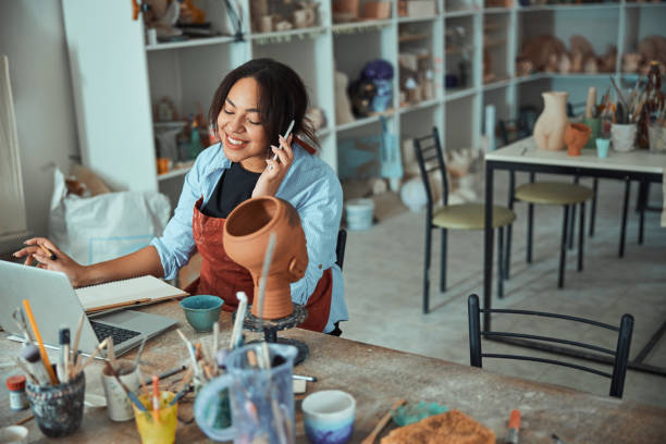 istock Cheerful female potter talking on cellphone in pottery workshop 1319479728