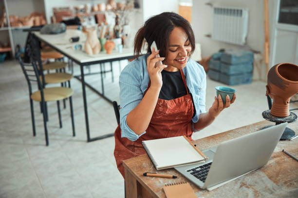 istock Cheerful woman having phone conversation in pottery workshop 1319479729