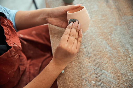 Female potter hands sanding clay pot in workshop