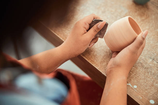 istock Craftswoman hands sanding clay pot in pottery workshop 1319479752