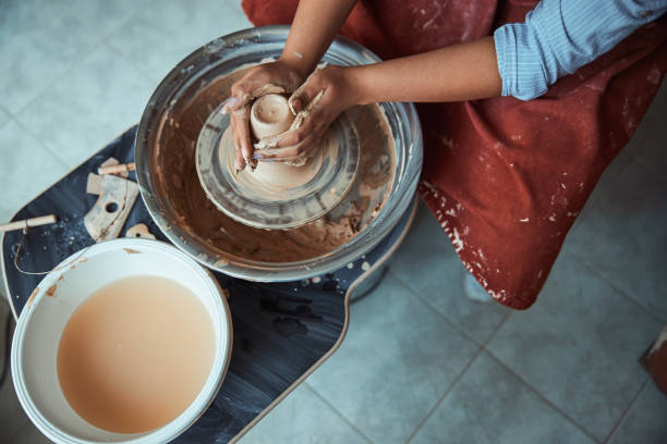 istock Female hands throwing clay pot on pottery wheel 1319481660