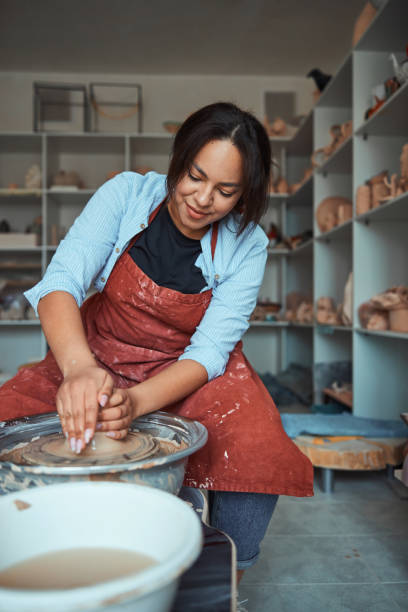 istock Charming young woman throwing clay pot on pottery wheel 1319481663