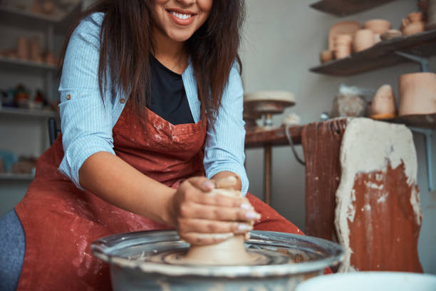 jeune femme joyeux faisant la poterie dans l’atelier - throwing wheel photos et images de collection