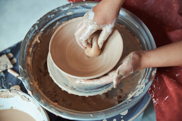 istock Female potter hands wiping clay bowl with sponge 1319481699