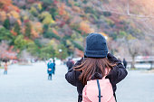 写真を撮る幸せな女性観光客は、嵐山でカメラで山を葉、京都の若いアジア人旅行者が訪れる。秋秋シーズン、休暇、休日、観光コンセプト