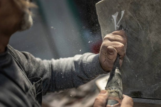 istock Close-up of a stonemason using a chisel to engrave a letter into a stone 1319483936