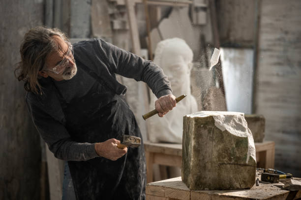 istock Sculptor using hammer and chisel on a piece of stone 1319483970