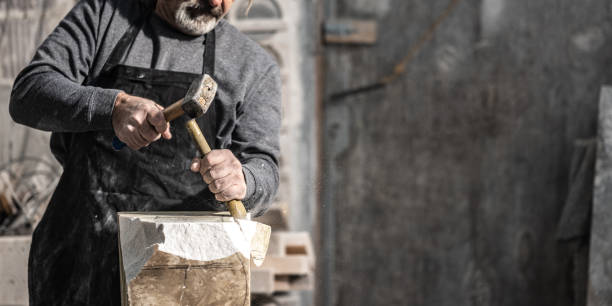 istock Caucasian stonemason shaping a rock with a hammer and chisel 1319483978