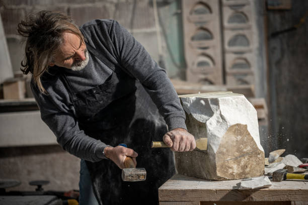 istock Sculptor using hammer and chisel on a piece of stone 1319483988