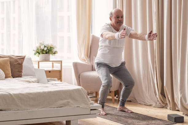 istock Senior man practicing yoga at home doing Chair pose, Utkatasana 1319484177