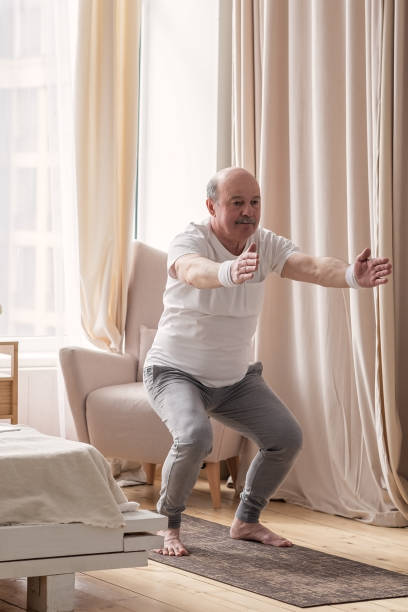istock Senior man practicing yoga at home doing Chair pose, Utkatasana 1319484214