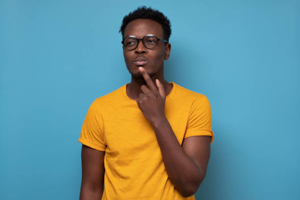 istock Young african man in glasses thinking over blue background 1319485934