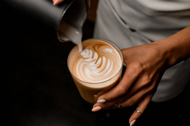 primo piano del modello barista che disegna delicatamente il latte in vetro con latte - espresso coffee cafe making foto e immagini stock
